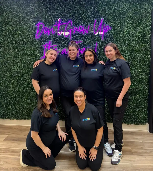 Efros Orthodontics team in front of a neon sign wall